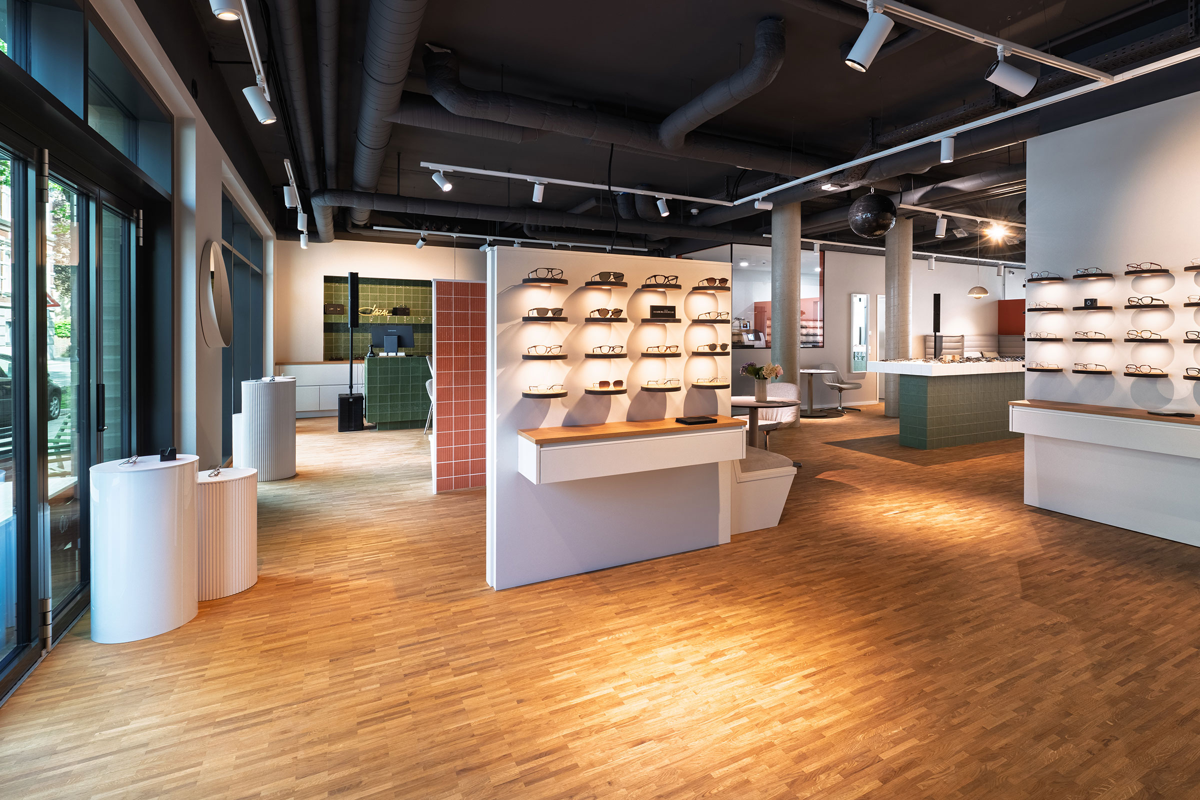 Verkaufsraum von Optik Berg mit Holzboden, Fensterfront und beleuchteten Brillenregalen